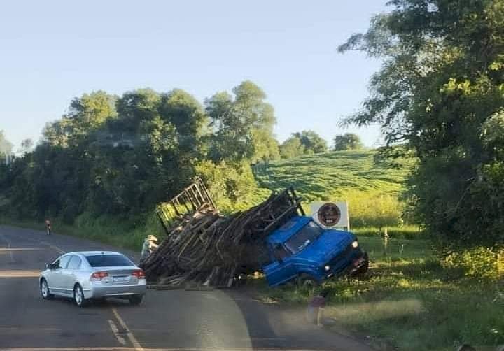 Caminhão carregado de lenha tomba